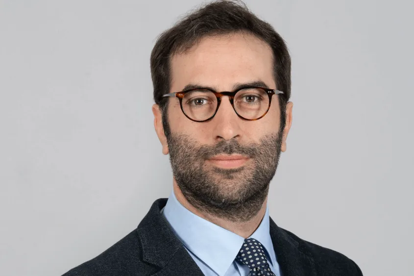 Retrato de Carlos Cuerpo, ministro de Economía, con gafas y corbata, sobre fondo gris